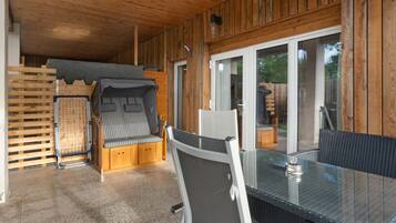 Una cabaña de madera con una mesa y sillas de vidrio, una cama litera y un gran ventanal que da al exterior.