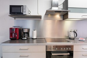 A modern kitchen with a microwave, coffee maker, kettle, and oven. - Apartment “Zum Segel” 1 with Private Terrace and Wi-Fi (Zadelsdorf)