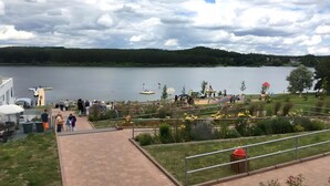 Une vue sur le lac, avec une promenade pavée, une pelouse parsemée de fleurs et un quai où sont amarrés des bateaux.