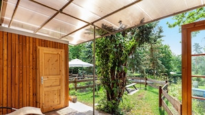 Een houten terras met een glazen deur naar een tuin.