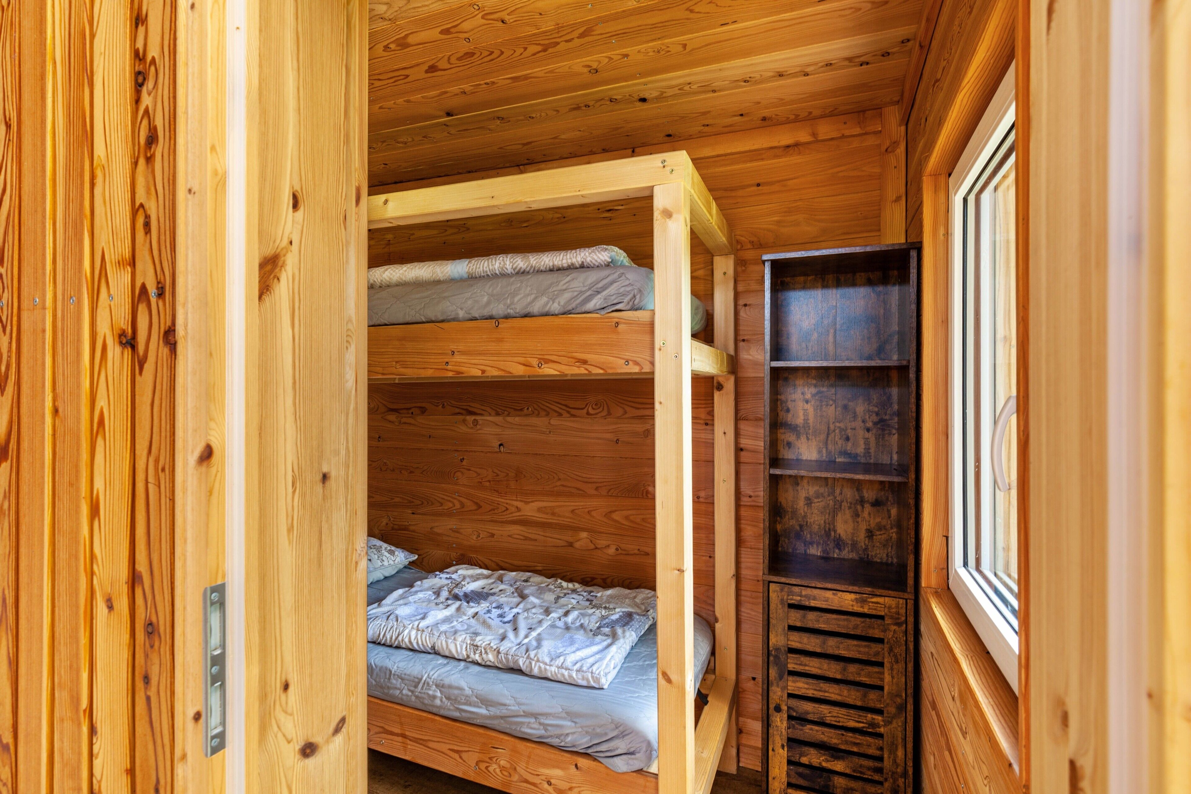 A wooden interior with bunk beds and a window.
