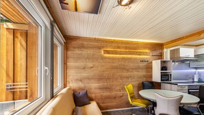 Een modern interieur met een bank, gele stoelen, een ronde tafel en een keukenhoek.