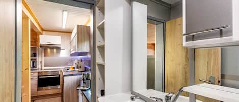 A modern kitchen with built-in appliances, a large sink, and a wooden interior.