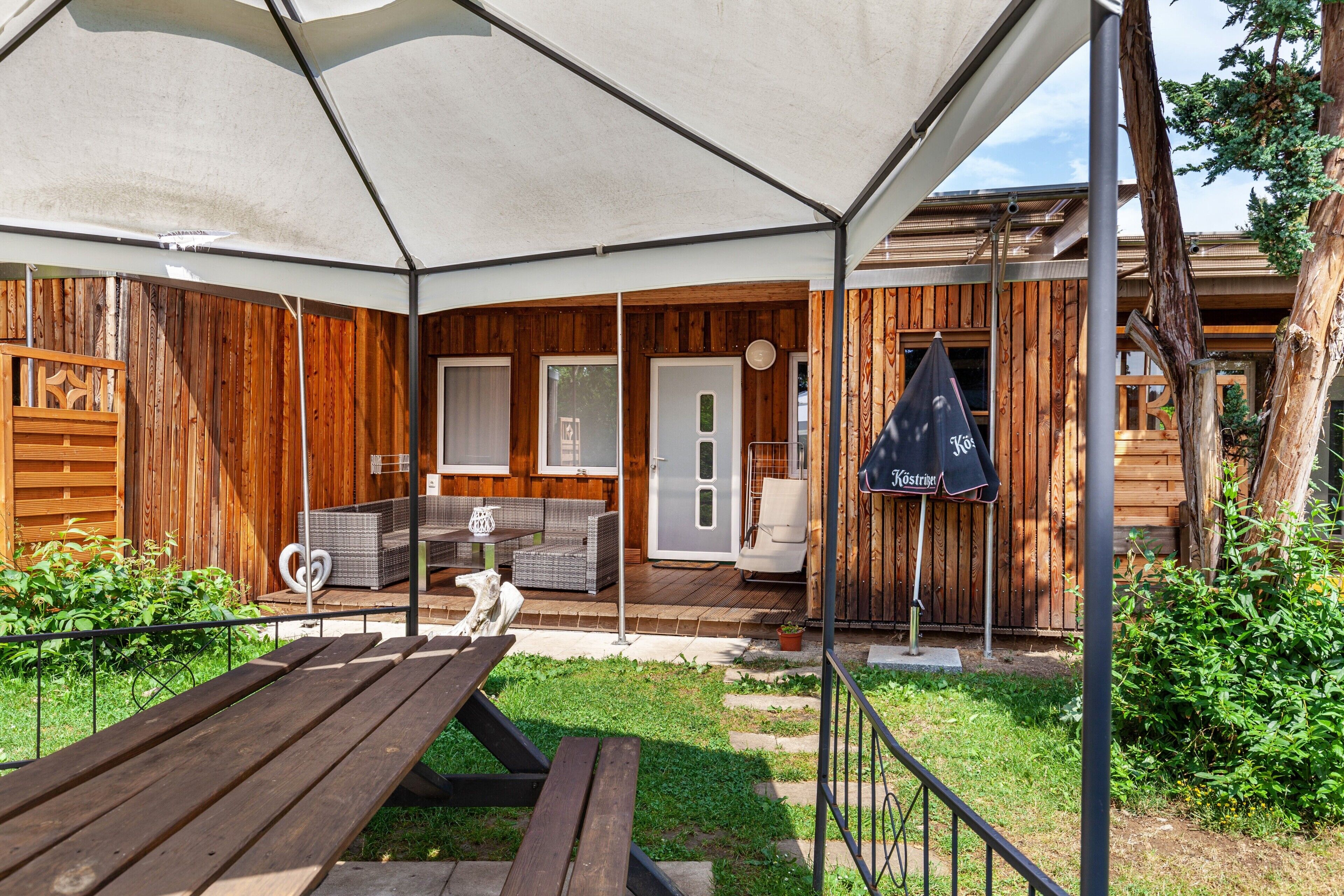 Une cabane en bois dotée d’un patio couvert, de meubles d’extérieur et d’un drapeau.