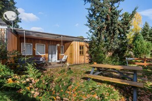 A wooden cabin with a patio, a satellite dish, and a picnic table.