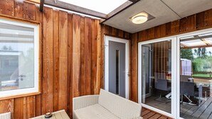 A wooden exterior with a glass door leading to an outdoor seating area.