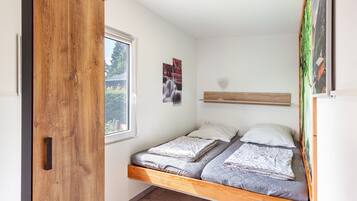 A compact bedroom with a bed, a window, and a wooden wardrobe.
