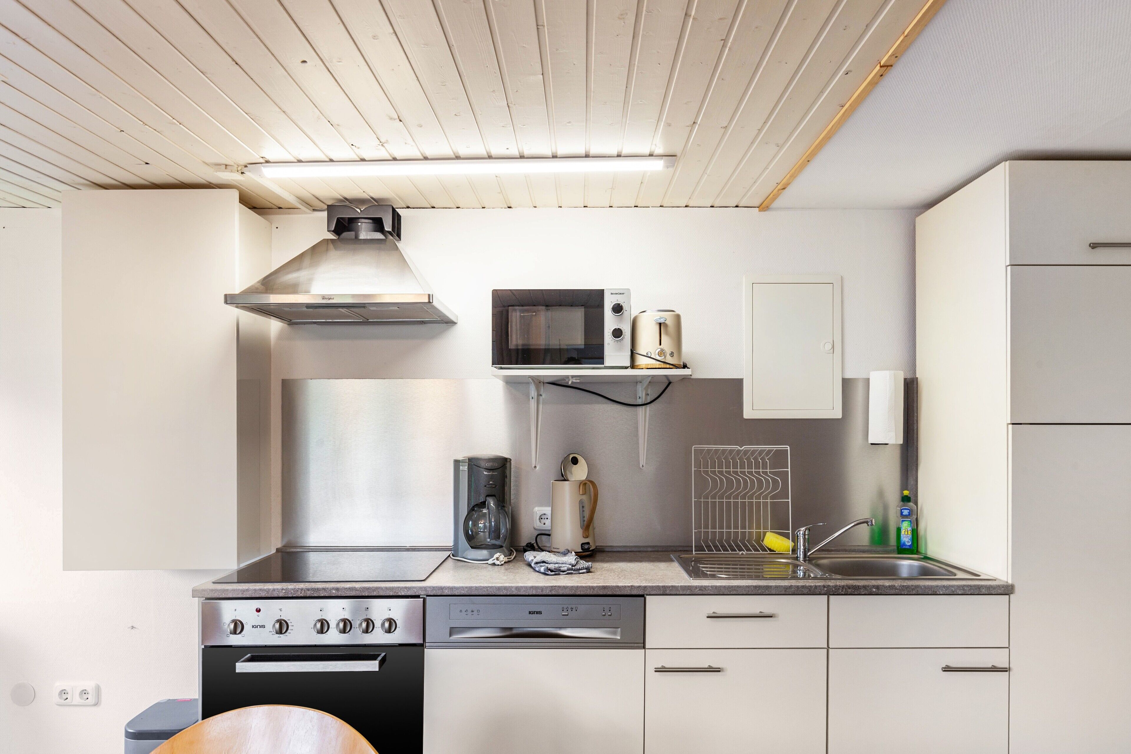 Una cucina moderna con cappa in acciaio inossidabile, microonde, macchina del caffè e lavastoviglie.