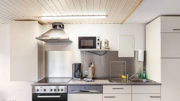 Una cucina moderna con cappa in acciaio inossidabile, microonde, macchina del caffè e lavastoviglie.
