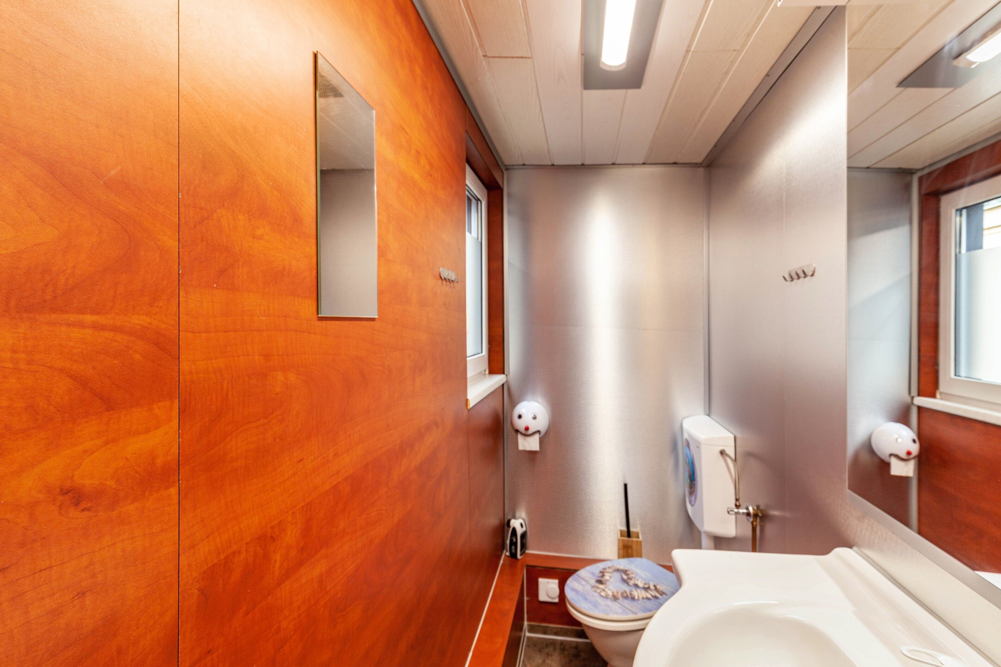 Une salle de bain avec des murs en bois, des toilettes, un lavabo et un miroir.