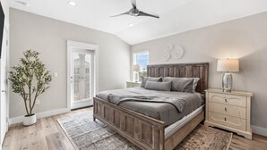 Ein Schlafzimmer mit Bett, Nachttisch, Lampe, Deckenventilator und einer Topfpflanze.