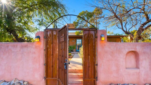A rustic entrance with a wooden gate, a welcome sign, and a number 415 sign above.