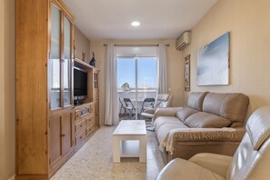 A living room with a sofa, a television, a cabinet, and a table.