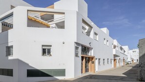 Ein modernes, weißes Gebäude mit Flachdach, großen Fenstern und einer sichtbaren Treppe.