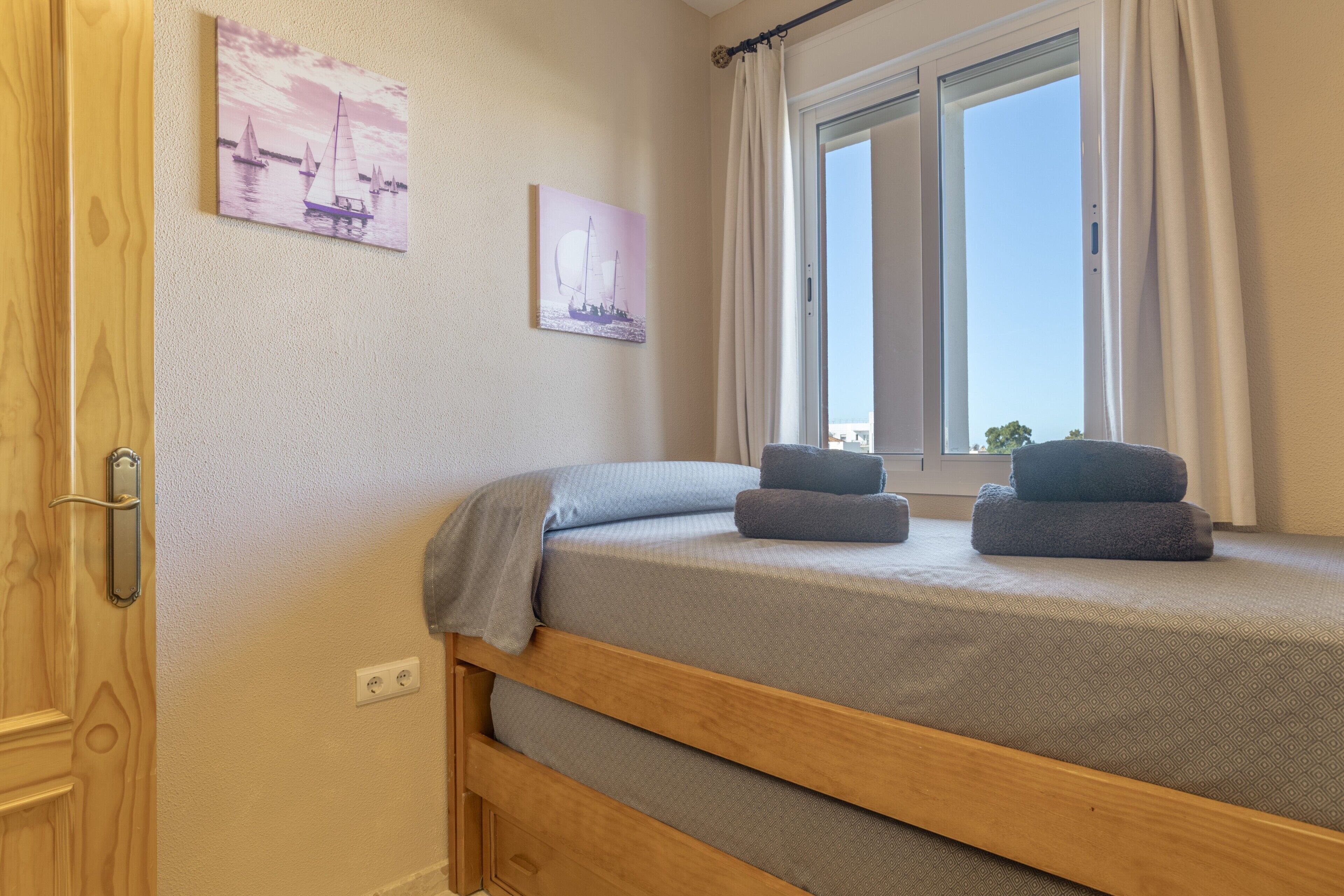 A bedroom with a bed, a window, and two wall-mounted pictures.
