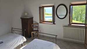 Une chambre avec deux lits, une commode, une chaise, une fenêtre donnant sur une piscine et un radiateur.