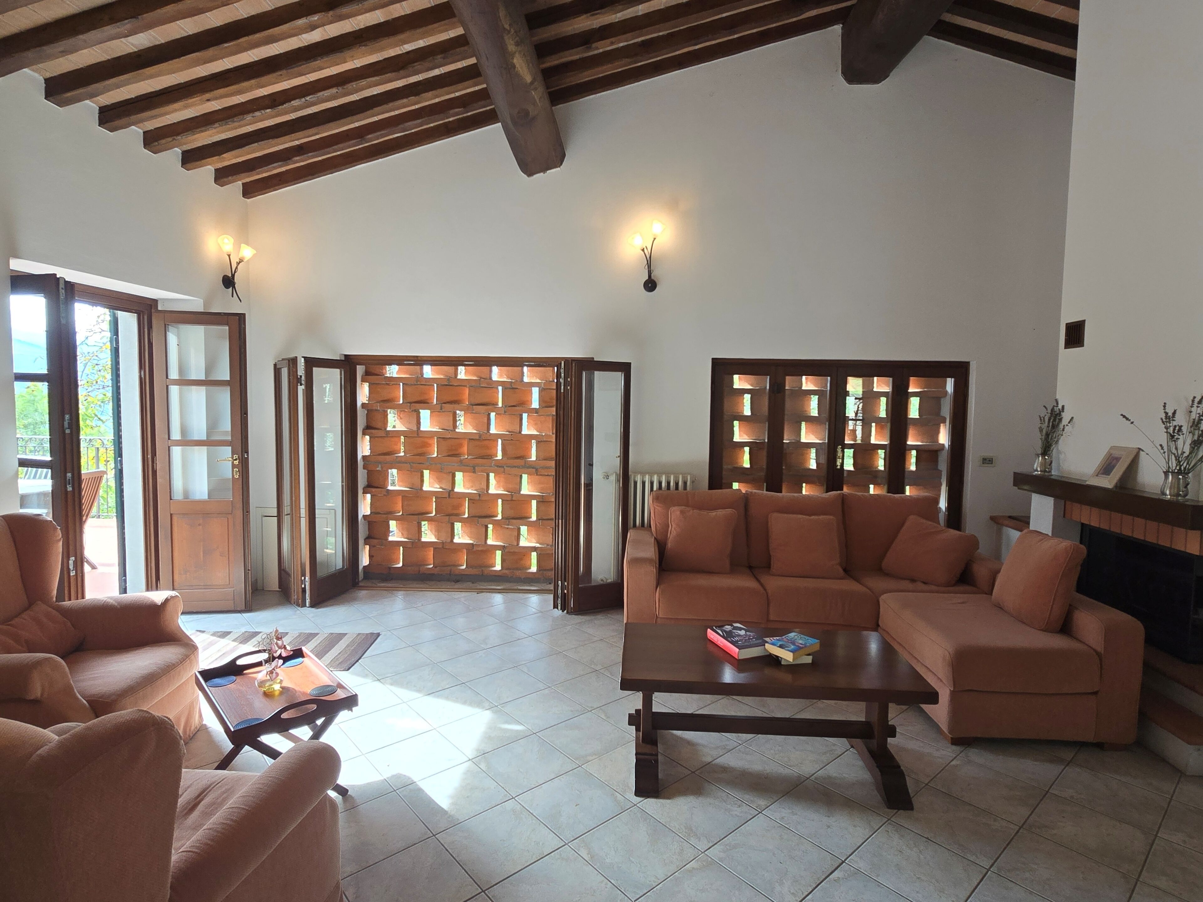 A spacious living room with a wooden ceiling, a sofa set, a coffee table, and a brick wall partition.