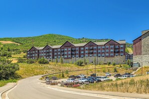 Un hotel de varios pisos con diseño moderno, situado en una ladera y con un área de estacionamiento frente a él.