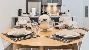 Un comedor con una mesa redonda lista para dos personas, con platos, vasos y cubiertos.