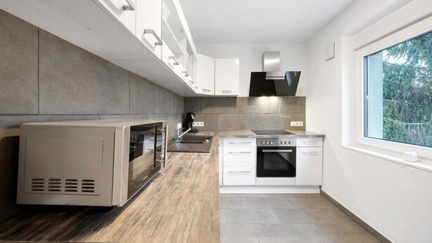 Una cocina moderna con electrodomésticos integrados, una ventana y vistas a zonas verdes.