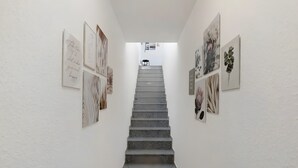 A staircase with artwork on the walls, leading to a room with a view.