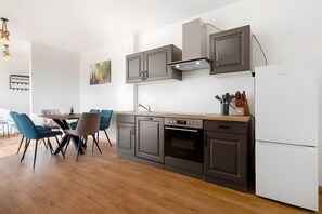 Una cucina moderna con mobili scuri, un frigorifero bianco e un'area pranzo con sedie blu.