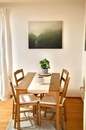 Une table à manger avec quatre chaises, une plante en pot et un tableau encadré accroché au mur.