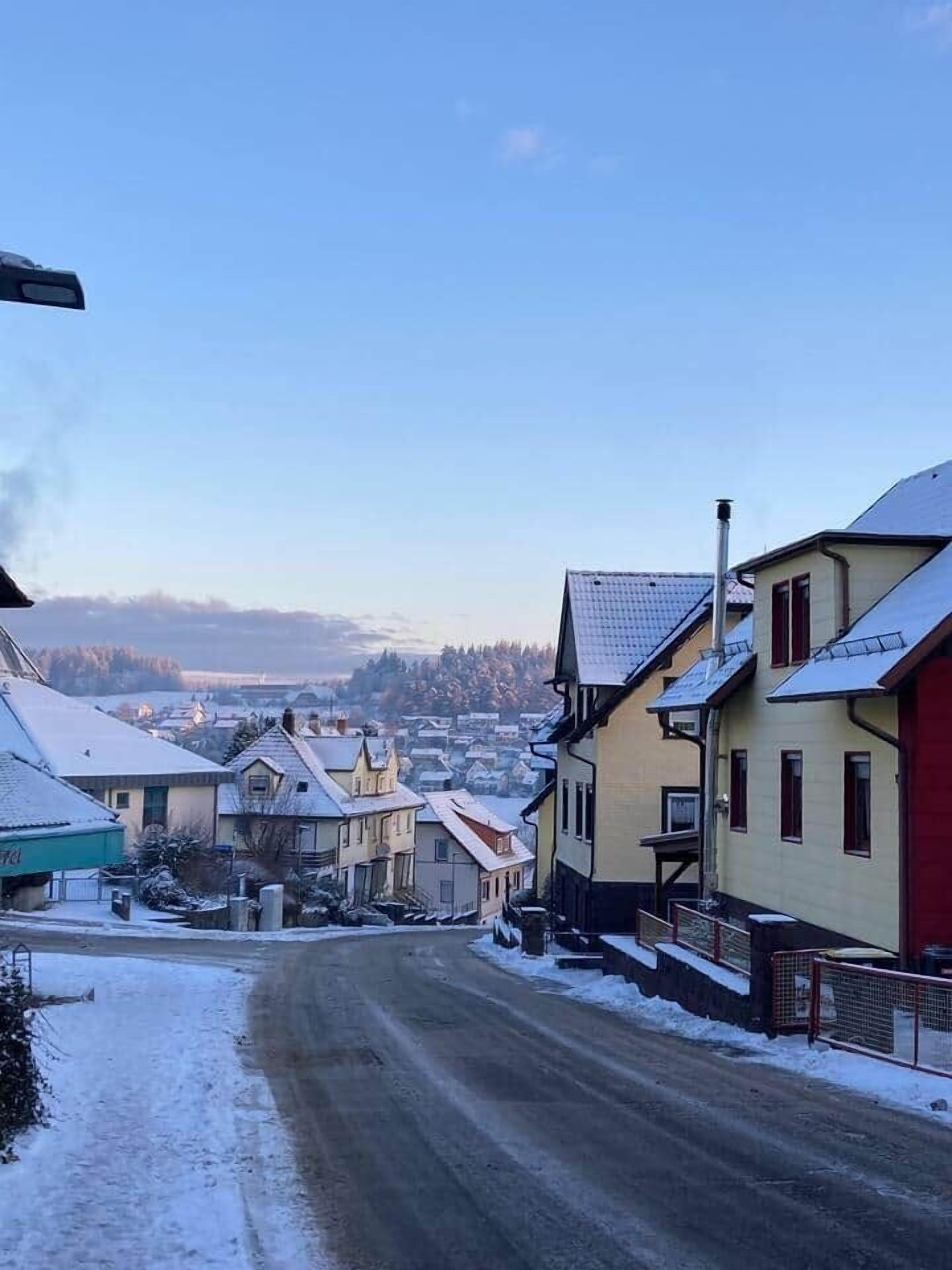 Une rue enneigée dans un quartier résidentiel, avec des maisons des deux côtés.