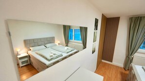 A bedroom with a bed, bedside tables, a dresser, and a window with curtains.