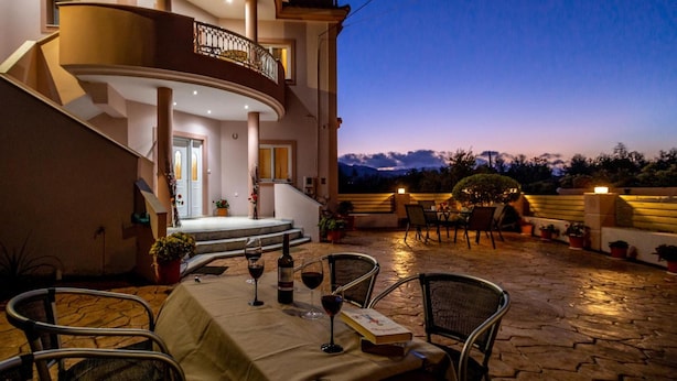A modern house with a curved staircase, outdoor seating, and a view of the mountains.