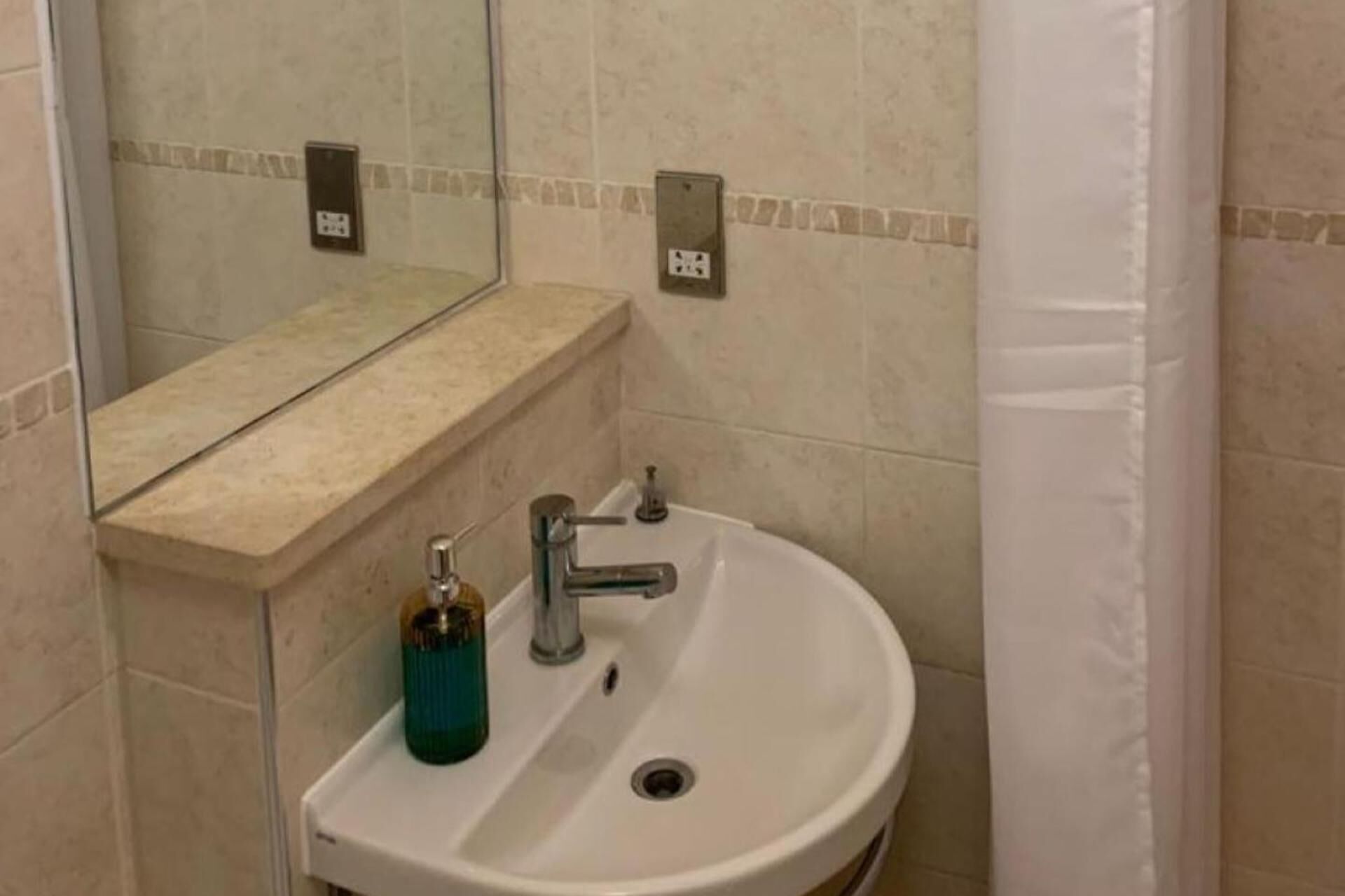 A bathroom with a white sink, a mirror, and a shower curtain.
