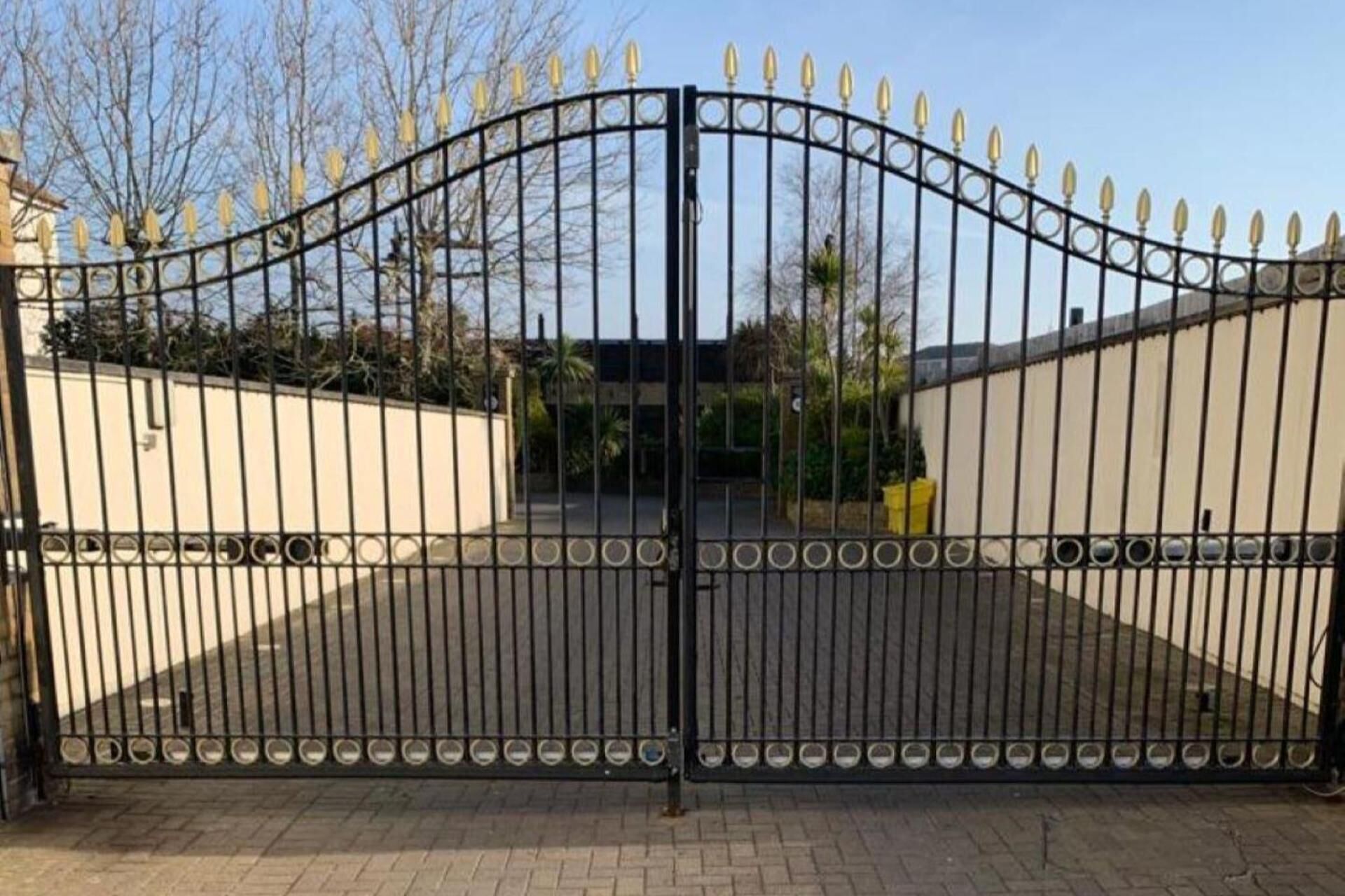 Una entrada porticada con arco curvo, flanqueada por muros y árboles.