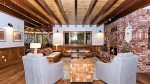 A cozy living room with a fireplace, wooden beams, and comfortable seating.