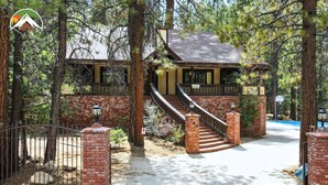 A two-story house with a brick exterior, a wooden staircase, and a fenced driveway.