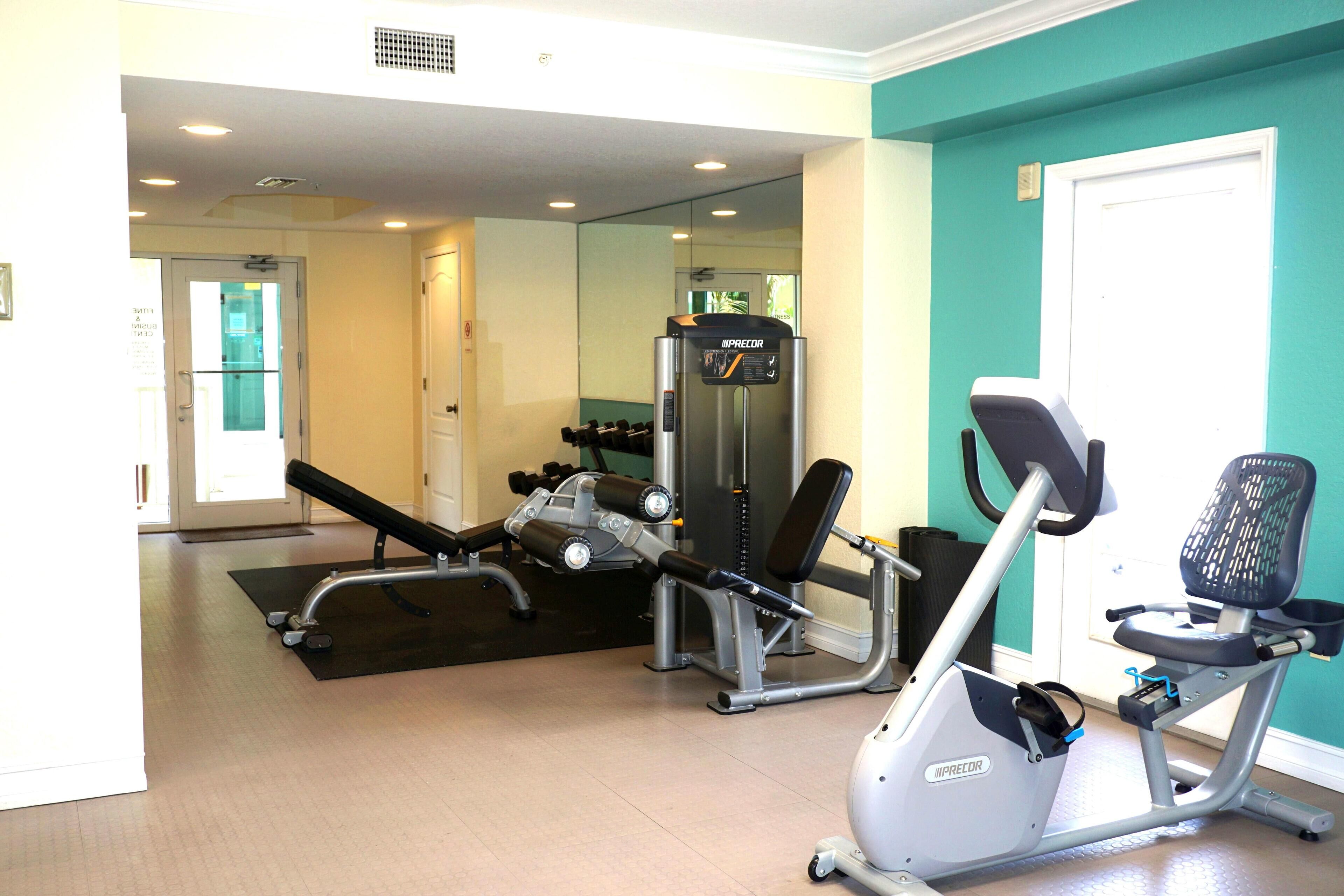 A gym with exercise equipment including a bench, a weight machine, and an elliptical trainer.