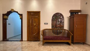 A lobby with a wooden bench, a decorative door, and a cabinet. - Lake View Residency (Puducherry)