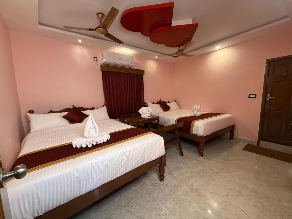 Habitación de hotel con dos camas, ventilador de techo, aire acondicionado y puerta de madera.