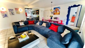 A modern living room with a sectional sofa, a coffee table, and a dining area with a red table and chairs. - Family & Fun! Pedestrian center near Lake and Ski (Gérardmer)