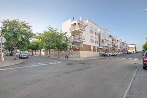 Un edificio residenziale a più piani con balconi, auto parcheggiate e cielo sereno.