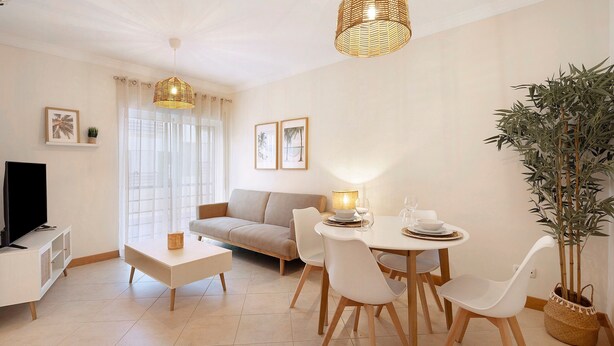 Una sala de estar moderna con un sofá, una mesa de comedor, sillas, un televisor y una planta en maceta.
