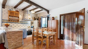 Una cucina con mobili in legno, zoccolo a piastrelle e porta in legno.