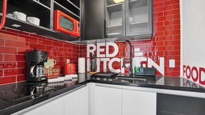 Una cucina con piastrelle rosse e bianche, una macchina per il caffè, un tostapane e un forno a microonde.