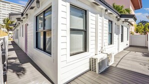 Un edificio bianco con ampie finestre, un pontile in legno e un condizionatore.