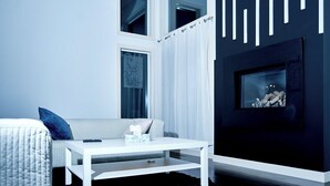 Una sala de estar moderna con un sofá blanco, una mesa de centro blanca y una chimenea negra.