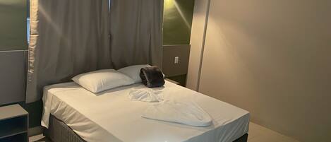 A neatly made bed with white linens, a pillow, and a folded garment on the bed.