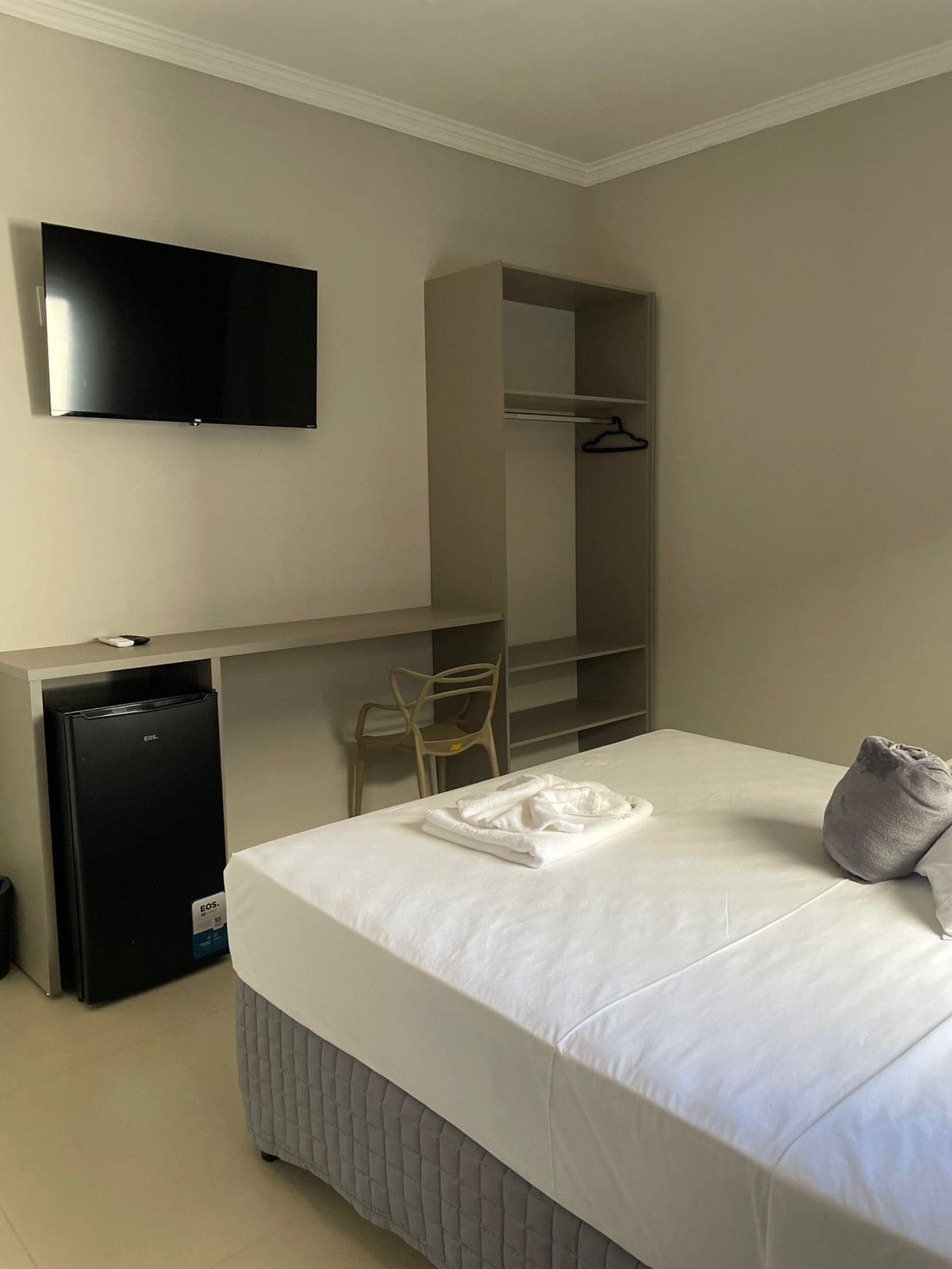 Habitación de hotel con cama, escritorio, silla, televisión y minibar.