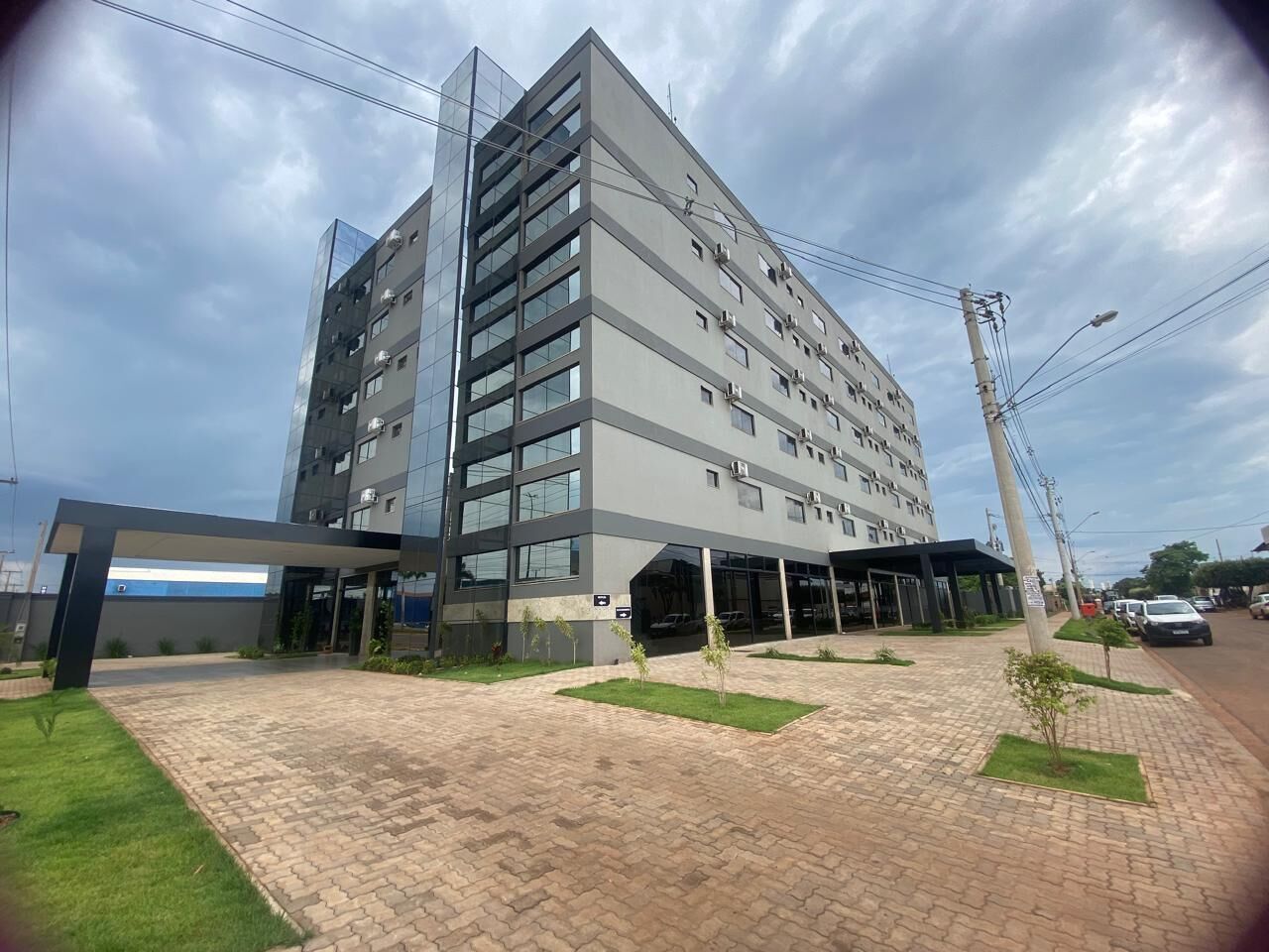 A modern multi-story building with a covered entrance and a paved courtyard.