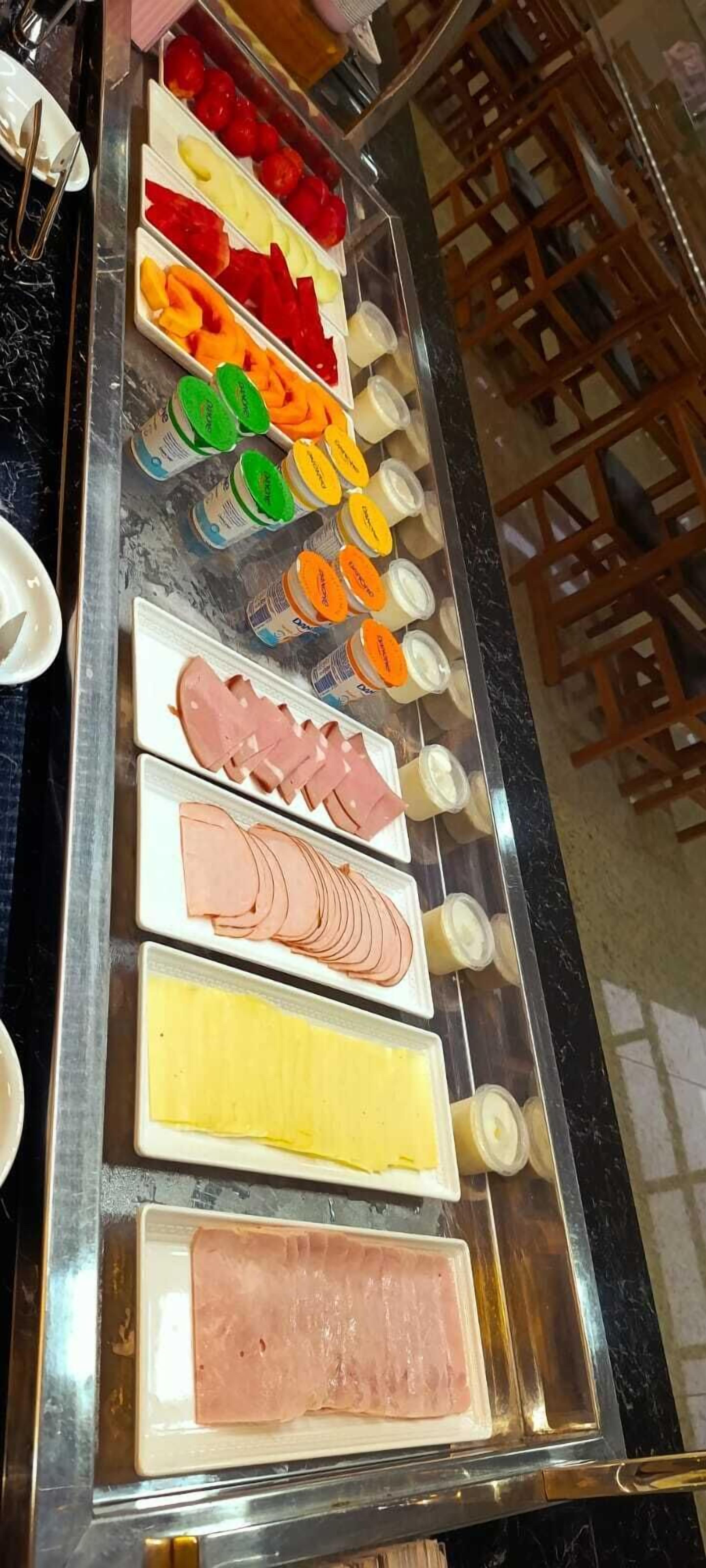 A buffet with various food items including fruits, cheeses, and meats.
