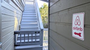 A staircase leading to a wooden deck with a sign indicating an Airbnb property. - Hill Country Retreat (Austin)