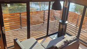 Une chambre moderne avec un canapé, une cheminée et une vue sur une terrasse en bois.